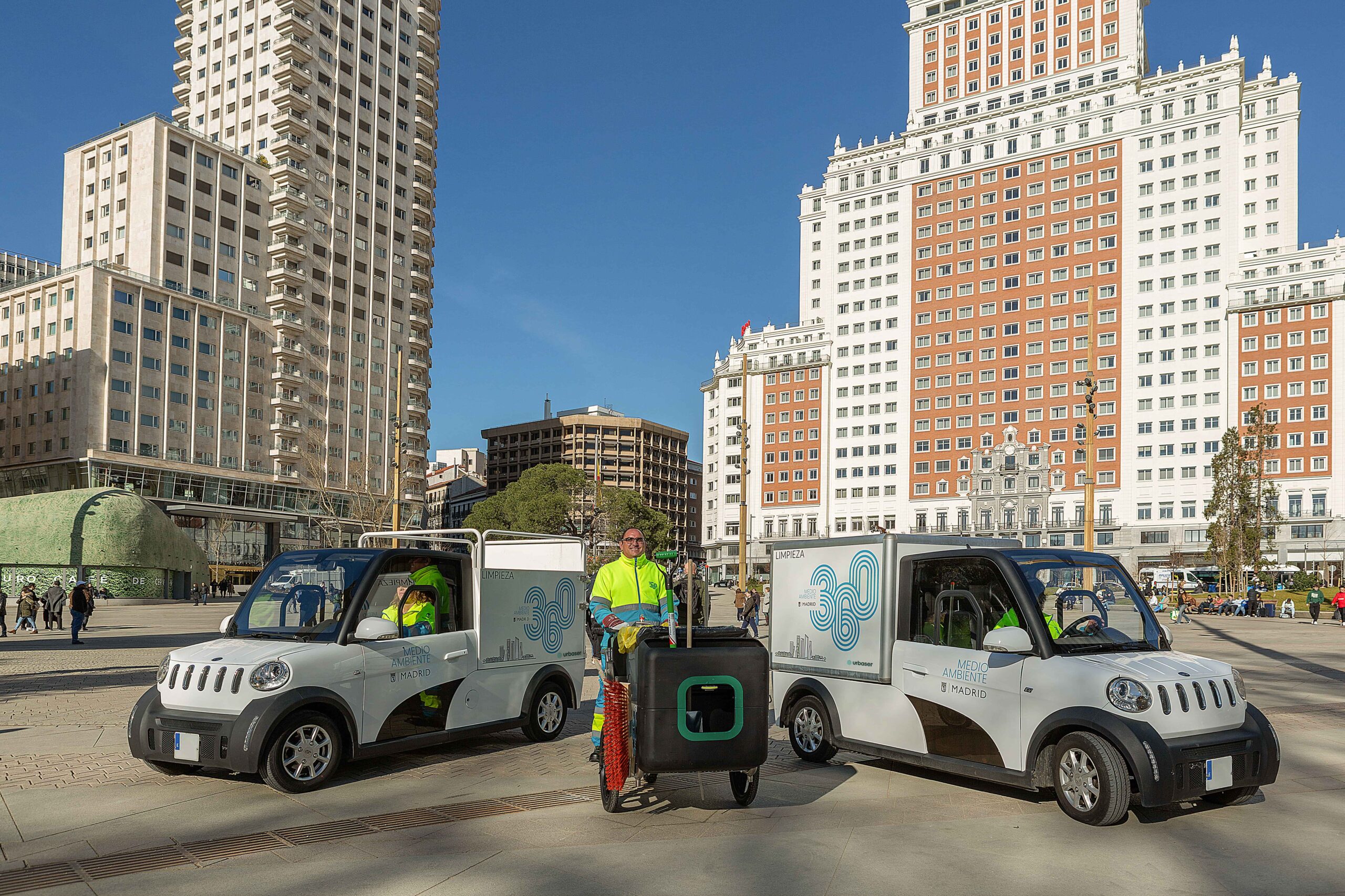 Dos vehículos eléctricos y trabajador de Urbaser con carrito en Plaza España de Madrid